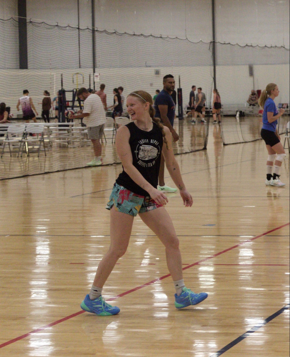 Omahotties player smiling mid-rally during indoor play