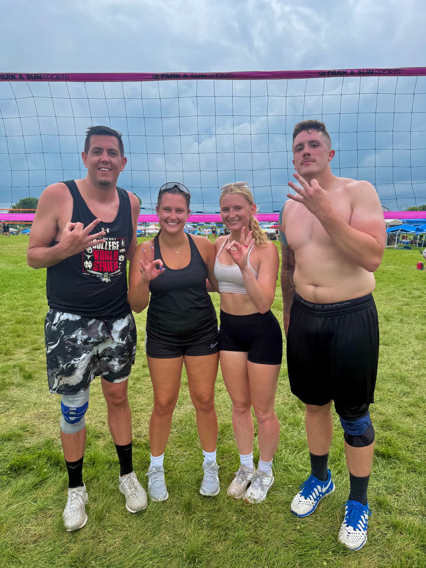 Omahotties teammates posing at the net after a grass tournament match